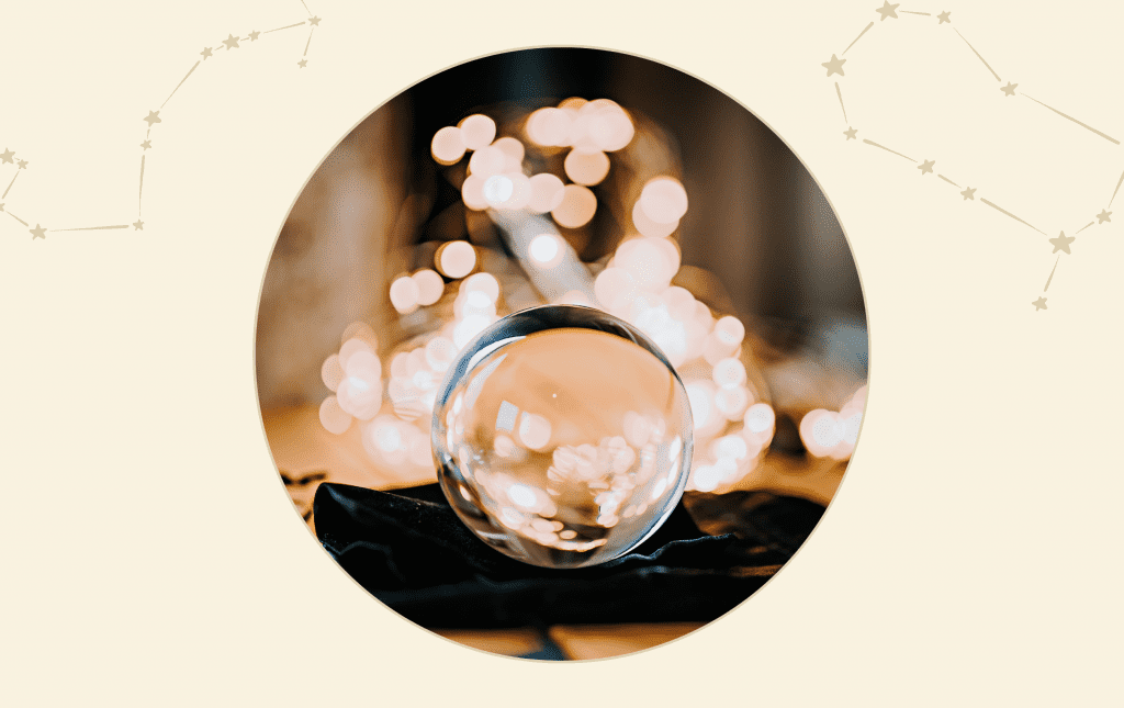 A clear crystal ball on a table with fairy lights in the background.