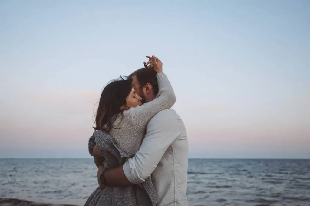 A man and a woman embracing each other in front of the sea.