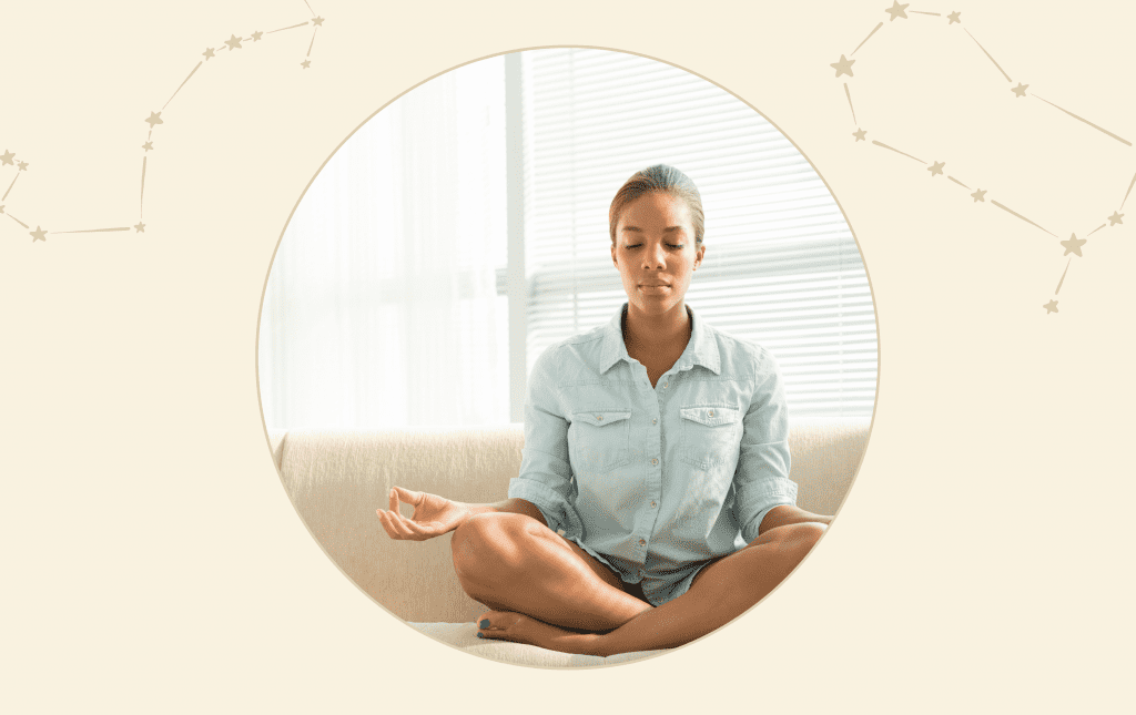 A woman sitting cross-legged with her eyes closed meditating.